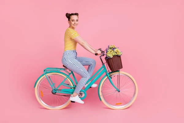 Foto de perfil em tamanho real de otimista agradável morena passeio de bicicleta desgaste t-shirt calças isoladas no fundo rosa — Fotografia de Stock