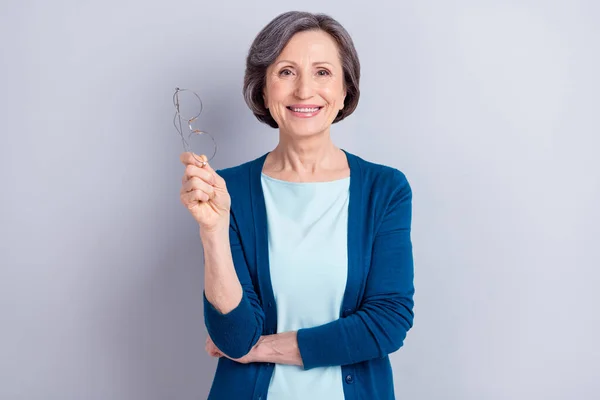Retrato fotográfico de una anciana feliz que lleva gafas con chaqueta azul sonriendo aislada sobre fondo de color gris —  Fotos de Stock