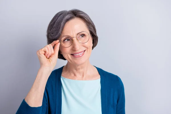 Foto av attraktiv trevlig drömmande gammal kvinna ser tomt utrymme bära glasögon isolerade på grå färg bakgrund — Stockfoto