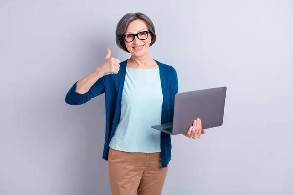 Portrait photo d'une femme d'affaires âgée avec des cheveux gris gardant ordinateur portable montrant signe pouce vers le haut isolé sur fond de couleur grise — Photo