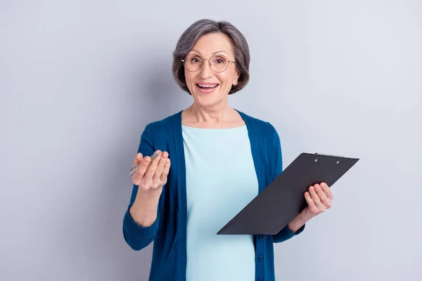Retrato fotográfico de una mujer de negocios mayor que mantiene la pluma del portapapeles hablando en una entrevista aislada sobre un fondo de color gris —  Fotos de Stock