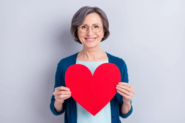 Foto retrato de mulher de negócios feliz sorrindo mantendo coração vermelho em forma de cartão postal isolado no fundo de cor cinza — Fotografia de Stock