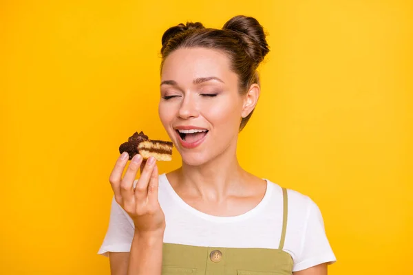 Retrato de atraente sonhador menina alegre mordendo pedaço de bolo confeitaria deliciosa isolado sobre fundo de cor amarela brilhante — Fotografia de Stock