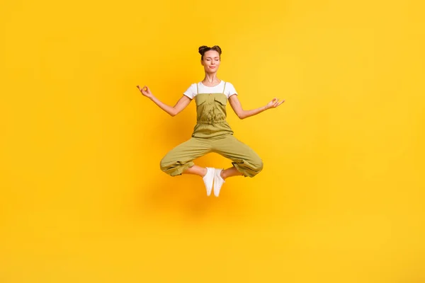 Teljes hossz testméret kilátás elég nyugodt álmodozó lány jumping meditáló ül lótusz póz elszigetelt felett élénk sárga színű háttér — Stock Fotó
