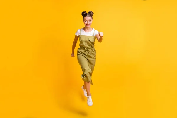 Фото смешно положительный прыжок леди бежать смотреть камеры носить зеленый общий обувь изолированный желтый фон — стоковое фото