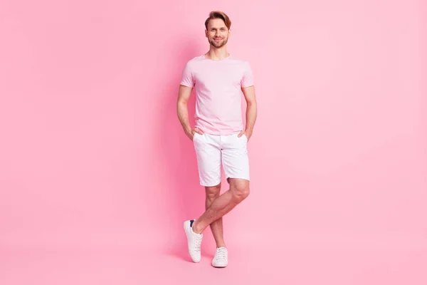 Photo of charming sweet young guy wear casual clothes smiling arms shorts pockets isolated pink color background — Stock Photo, Image