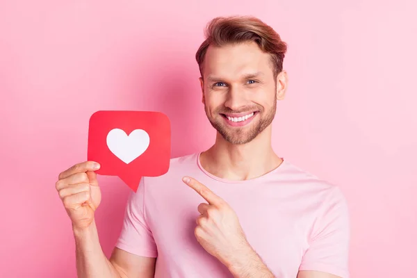 Retrato de homem alegre indicar dedo segurar papel como cartão isolado no fundo cor-de-rosa — Fotografia de Stock