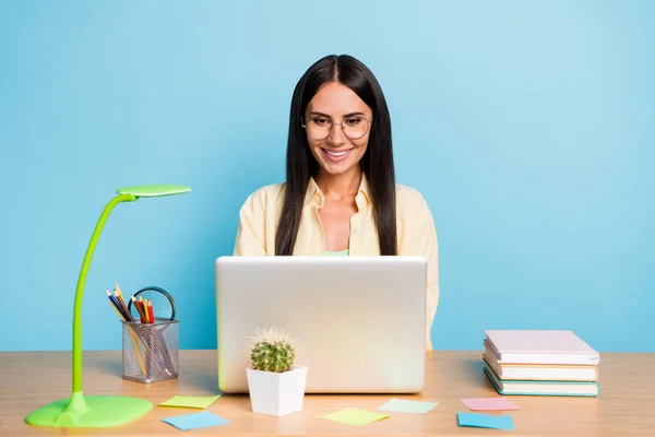 Retrato de menina alegre focada atraente usando laptop preparando apresentação relatório de tarefa isolado sobre fundo de cor azul brilhante — Fotografia de Stock