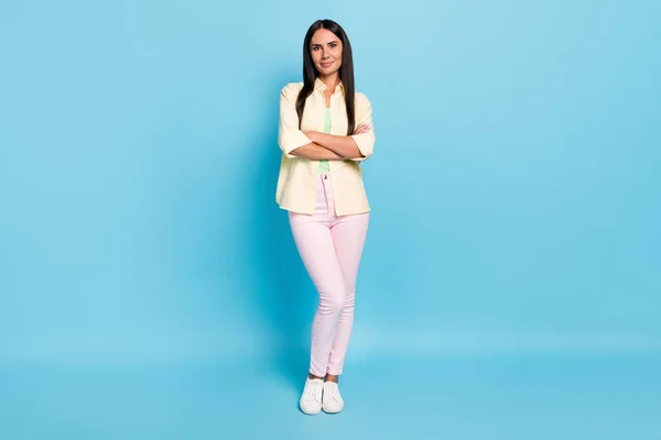 Retrato de tamaño completo de encantadora joven satisfecha de pie cruzó las manos mirada cámara aislada sobre fondo de color azul —  Fotos de Stock