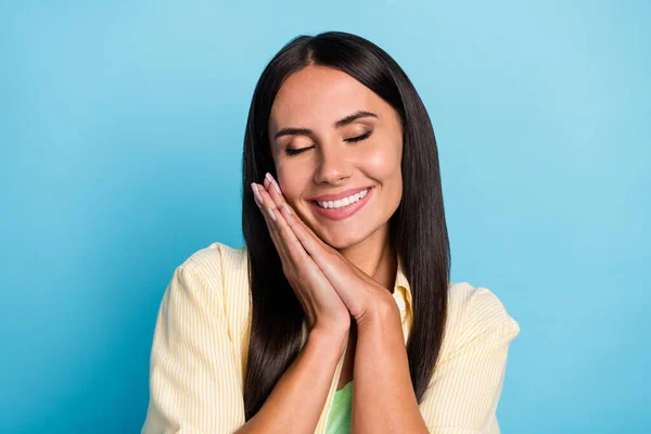 Retrato de linda menina alegre olhos fechados dente sorriso braços dobrados palmas na bochecha isolado no fundo de cor azul — Fotografia de Stock