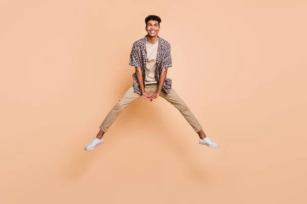 Foto de tamaño completo de la persona de piel oscura despreocupada saltando alto divertirse aislado sobre fondo de color beige — Foto de Stock