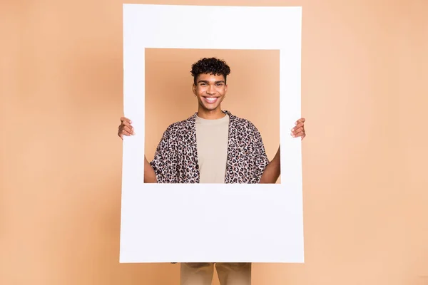 Foto de tipo optimista morena sostiene cartel usar pantalones de camisa modernos aislados sobre fondo de color beige — Foto de Stock