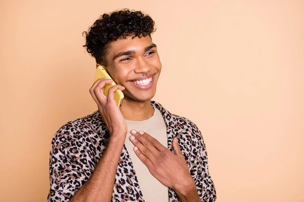 Foto de tío optimista morena hablar teléfono mano pecho desgaste camisa moderna aislada sobre fondo beige — Foto de Stock