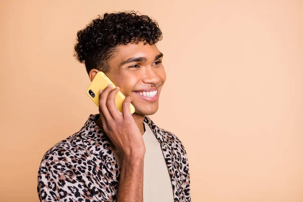 Foto de perfil de un chico optimista moreno hablar teléfono llevar camisa moderna aislada sobre fondo beige — Foto de Stock