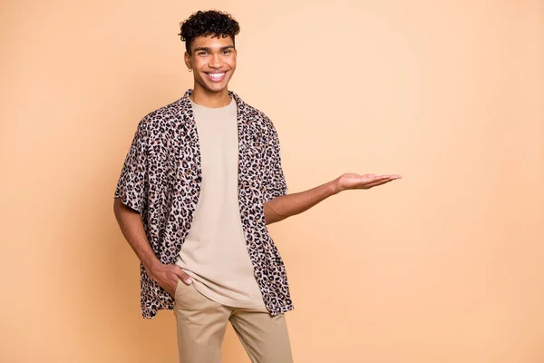 Foto van brunet optimistische man houden lege ruimte dragen moderne shirt geïsoleerd op beige kleur achtergrond — Stockfoto