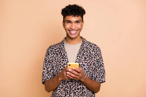 Portret van brunet optimistische man houden telefoon dragen modern shirt geïsoleerd op pastel beige kleur achtergrond — Stockfoto