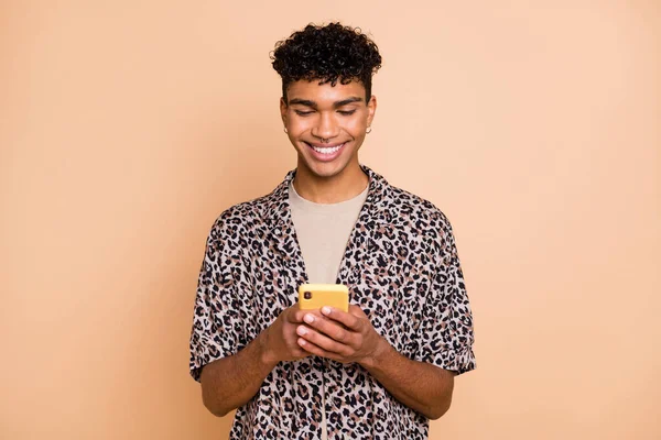 Portret van positieve jonge donkere huid jongen stralen glimlach typen blog post commentaar isoleren don beige kleur achtergrond — Stockfoto