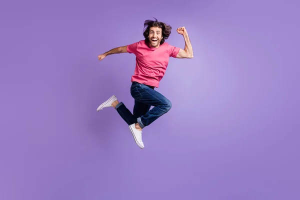 Pełna długość zdjęcie cute funky młody człowiek nosić różowy t-shirt skoki działa szybko izolowane fioletowy kolor tła — Zdjęcie stockowe