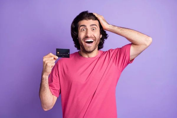Foto de impressionado agradável morena cara segurar cartão desgaste rosa t-shirt isolado no fundo cor violeta pastel — Fotografia de Stock