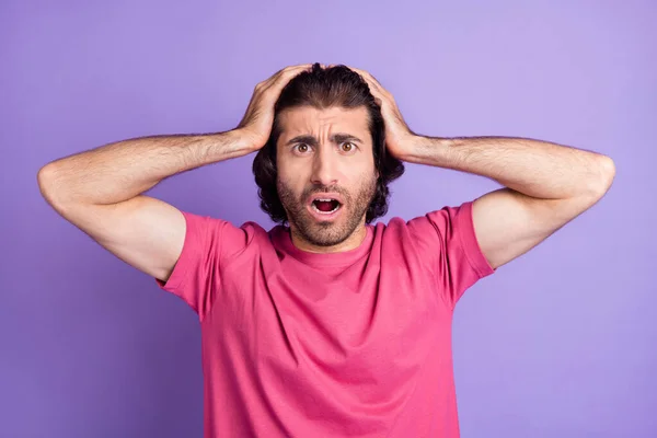 Foto di infelice impressionato bel ragazzo brunetta mani testa indossare rosa t-shirt isolato su sfondo di colore viola pastello — Foto Stock