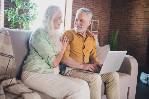 Foto apagado feliz positivo viejo gente sentarse sofá buen humor sentarse sofá uso portátil en el interior de la casa apartamento — Foto de Stock