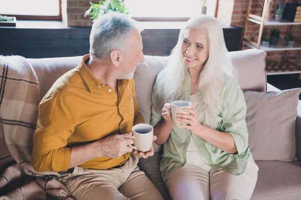 Foto de feliz positivo alegre anciana y hombre sentarse sofá beber café buen humor en el interior de la casa — Foto de Stock