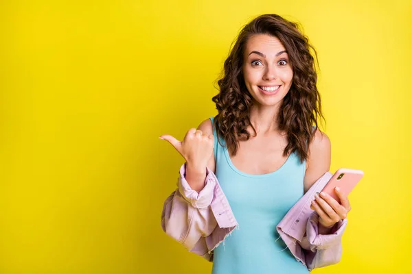 Foto van vrolijke glimlachen vrolijke mooie meisje wijzen vinger copyspace reclame product geïsoleerd op gele kleur achtergrond — Stockfoto