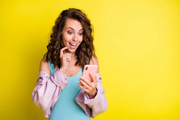 Retrato de atractiva chica de pelo ondulado asombrado alegre utilizando dispositivos de navegación medios web aislados sobre fondo de color amarillo brillante — Foto de Stock
