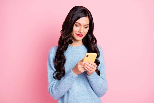 매력적 인 긍정적 인 여성의 사진 휴대폰 타이핑 댓글 이 핑크 색 배경에 고립된 스웨터를 입고 있는 것처럼 보인다 — 스톡 사진