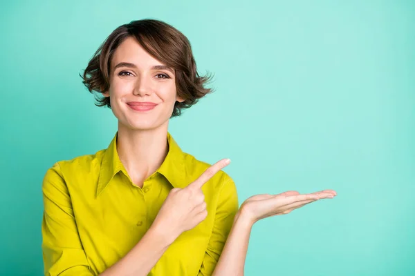 Foto retrato de menina bonito segurando espaço em branco na mão mostrando o dedo sorrindo isolado no fundo cor teal vívido — Fotografia de Stock