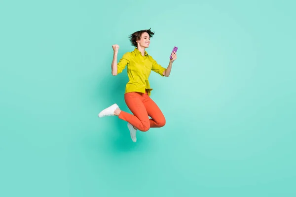 Фотографія повного розміру тіла, що стрибає з високою жінкою, тримаючи жест смартфона, як переможець, ізольований яскравий кольоровий фон з сльозами — стокове фото