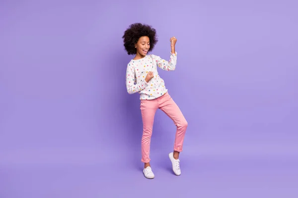 Foto de corpo inteiro da menina de pele escura feliz levantar punhos fechar os olhos comemorar o desgaste calças rosa isolado no fundo de cor roxa — Fotografia de Stock