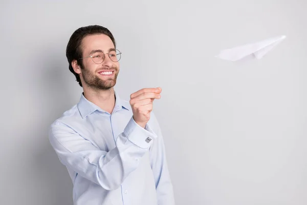 魅力的な陽気な男の肖像専門家は、グレーのパステルカラーの背景に隔離された紙飛行機レジャー投げ — ストック写真