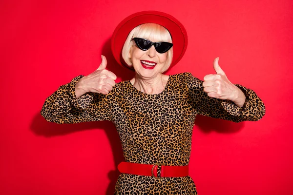 Фото веселих чарівних красивих старих жінок, які показують великі пальці вгору, рекомендують погодитися ізольовано на червоному тлі — стокове фото