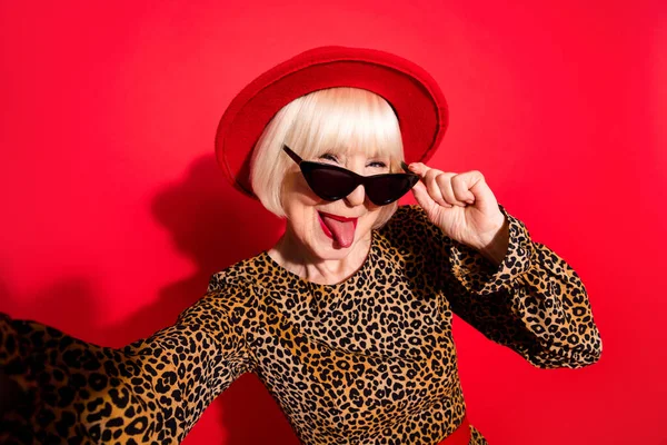 Foto bahagia menarik wanita tua yang funky mengambil selfie menjulurkan lidah Membuat wajah lucu terisolasi di latar belakang warna merah — Stok Foto