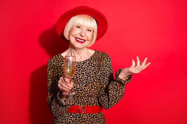 Фото веселой пожилой женщины счастливой позитивной улыбки пить шампанское тост ура изолированы на красном фоне — стоковое фото