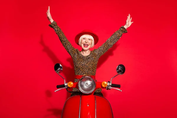 Foto van opgewonden oude vrouw gelukkig positieve glimlach rijden motor hand omhoog reizen geïsoleerd over rode kleur achtergrond — Stockfoto