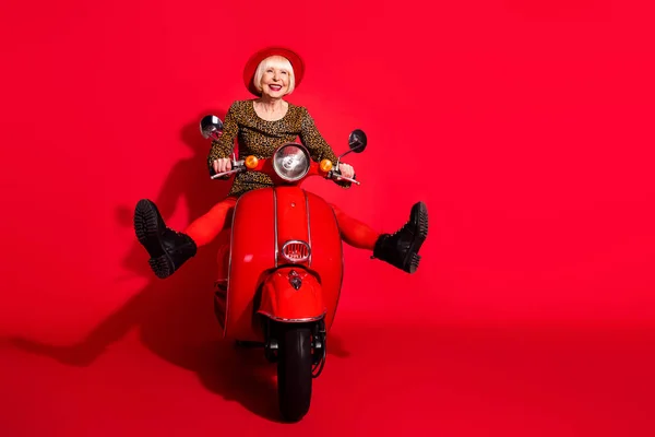 Full size foto van opgewonden senior vrouw gelukkig positieve glimlach bestuurder motor reizen snelheid geïsoleerd over rode kleur achtergrond — Stockfoto
