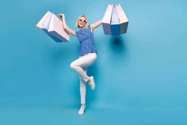 Full storlek foto av ung flicka glad positiv leende kund köpare hålla shoppingpåsar isolerade över blå färg bakgrund — Stockfoto