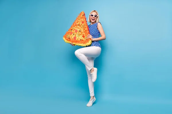 Helkroppsfoto av ung glad flicka glad positiv leende hålla papper pinata italiensk pizza smaskig isolerad över blå färg bakgrund — Stockfoto