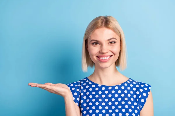 Fénykép a fiatal lány boldog pozitív mosoly bizonyítani kéz termék promo ajánlat elszigetelt felett kék színű háttér — Stock Fotó