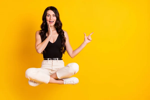 Volledige lengte lichaam grootte foto van vrouw zitten op stoel verbaasd wijzen lege ruimte aanraken wang geïsoleerd op helder gele kleur achtergrond — Stockfoto