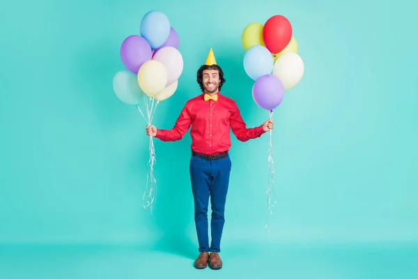 Πλήρης φωτογραφία μέγεθος του χαρούμενου χαμογελαστού όμορφος άντρας φορούν κώνο καπέλο κρατήσει μπαλόνια γιορτάσουν τα γενέθλια απομονώνονται σε teal φόντο χρώμα — Φωτογραφία Αρχείου
