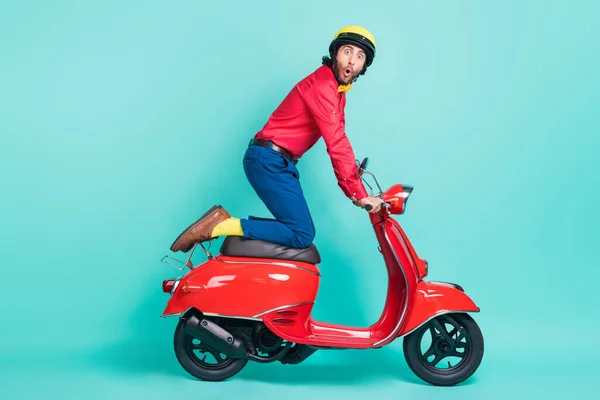 Foto sisi profil penuh dari pemuda lucu mengejutkan pria mengendarai sepeda motor terisolasi di latar belakang warna pirus — Stok Foto