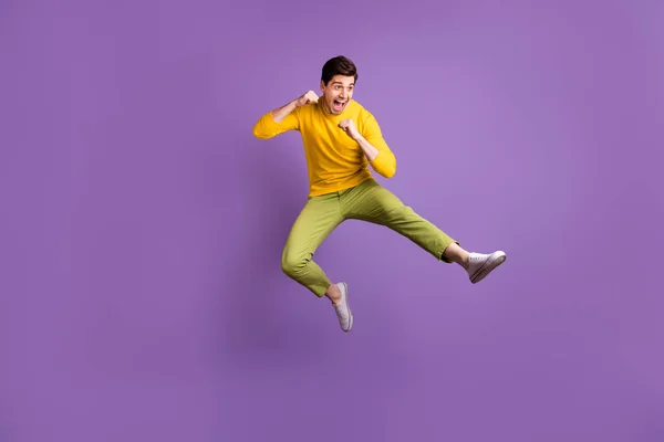 Foto em tamanho completo de jovem louco homem engraçado funky positivo fazendo karatê no ar saltando isolado no fundo de cor roxa — Fotografia de Stock