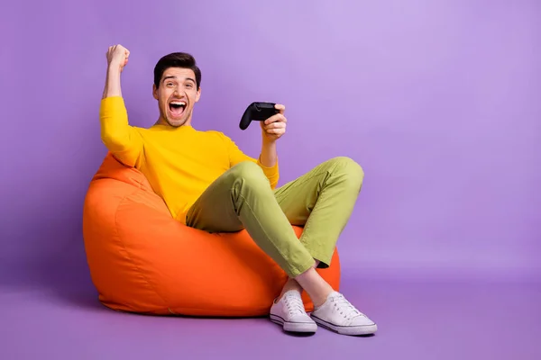 Full kropp profil sida foto av ung man glad glädje seger TV-spel joystick stol böna isolerad över violett färg bakgrund — Stockfoto