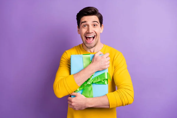 Φωτογραφία του όμορφος έκπληκτος άνδρας χέρια κρατήστε αγκαλιά giftbox ανοιχτό στόμα απομονωμένο σε βιολετί φόντο χρώμα — Φωτογραφία Αρχείου