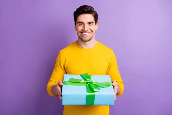 Φωτογραφία του νεαρού όμορφος χαρούμενος θετική καλή διάθεση χαμογελαστός χαρούμενος άνθρωπος να σας δώσει κουτί δώρου απομονώνονται σε μωβ φόντο χρώμα — Φωτογραφία Αρχείου