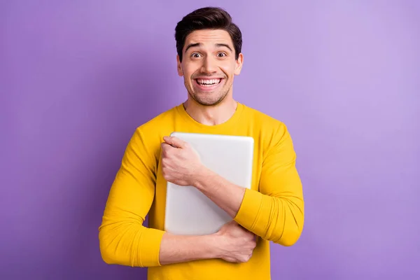 Zdjęcie pod wrażeniem młody człowiek uśmiech patrząc aparat ramiona trzymać uścisk laptop izolowany na fioletowym tle koloru — Zdjęcie stockowe