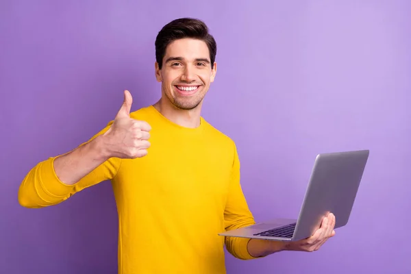 Zdjęcie przystojnego faceta ramię trzymać laptop pokazać kciuk w górę belki uśmiech odizolowany na fioletowym tle koloru — Zdjęcie stockowe